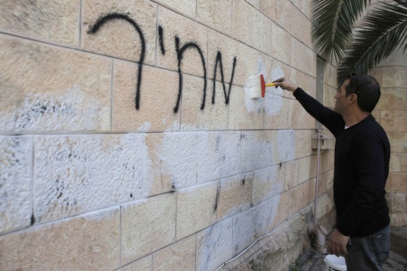 Ein Gemeindearbeiter entfernt am 9. Mai 2014 ein Hass-Graffiti von den Mauern einer orthodoxen Kirche in Jerusalem.&nbsp;