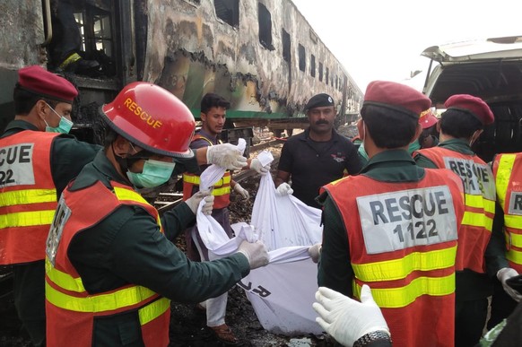 epa07961659 Rescue workers shift the bodies of the victims after a fire engulfed a passenger train near Rahim Yar Khan, Pakistan, 31 October 2019. Dozens were killed and more than 40 others injured af ...