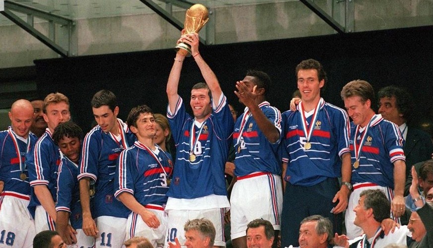 1998 holt Frankreich im eigenen Land den Weltmeistertitel. Der strahlende Zinédine Zidane hält die Trophäe in die Höhe.