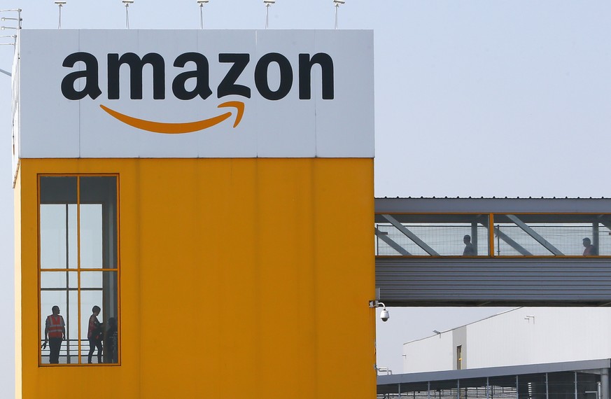 FILE - In this April 9, 2020, file photo, employees observe social distancing due to coronavirus, at the entrance of Amazon, in Douai, northern France. Amazon said Tuesday, Feb. 2, 2021, that CEO Jeff ...