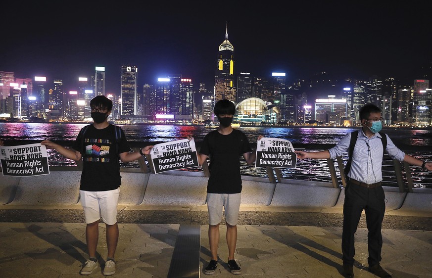 Demonstrators hold signs as they gather at the Tsim Sha Tsui waterfront in Hong Kong, Friday, Aug. 23, 2019. Demonstrators were planning to form a 40 kilometer (25 mile) long human chain Friday night  ...
