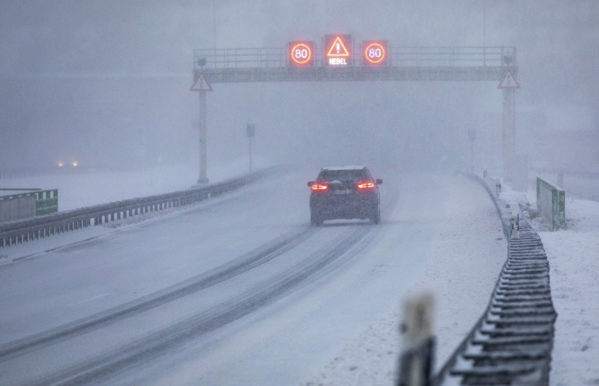 A car passes under a gantry advising of fog and speed limits on the snow-covered main road in Zella-Mehlis, Germany, Saturday Feb. 6, 2021. Bad weather has impacted on much of Germany. (Bernd Marz/dpa ...