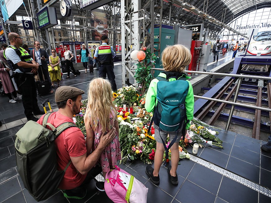 Passanten legen am Gleis im Frankfurter Hauptbahnhof, an dem der achtjährige Bub starb, Blumen nieder.