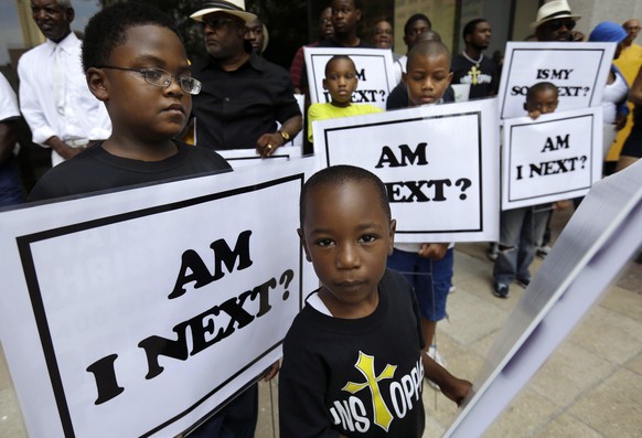 FILE - In this July 20, 2014 file photo, Alvin Duplessis, 10, left, and Thomas McGriff, 5, foreground, hold signs with others from the Watson Memorial Teaching Ministries Church of New Orleans, at a r ...