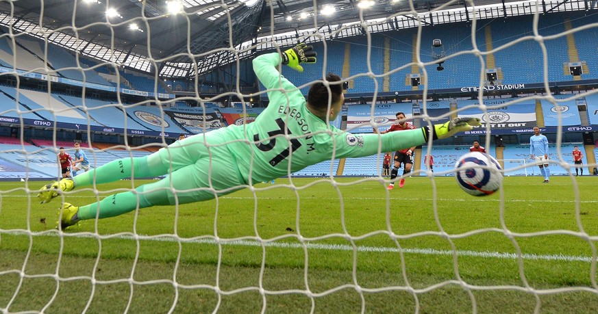epa09059826 Bruno Fernandes of Manchester United scores the opening goal with a penalty kick against Manchester City goalkeeper Ederson during the English Premier League soccer match between Mancheste ...