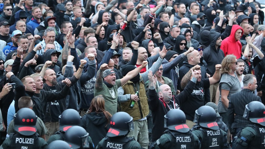 27.08.2018, Sachsen, Chemnitz: Polizisten stehen in der Innenstadt am Karl-Marx-Monument bei einer Kundgebung der rechten Szene, um ein Aufeinanderprallen von rechten und linken Gruppen zu verhindern. ...