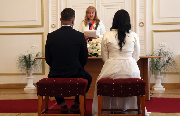 epa08328788 Groom Gyorgy David Jablonovszky (L) and his bride Timea Jablonovszky (R) face a marriage registrar (C) as they attend their wedding ceremony at the town hall of Miskolc, Hungary, 28 March  ...