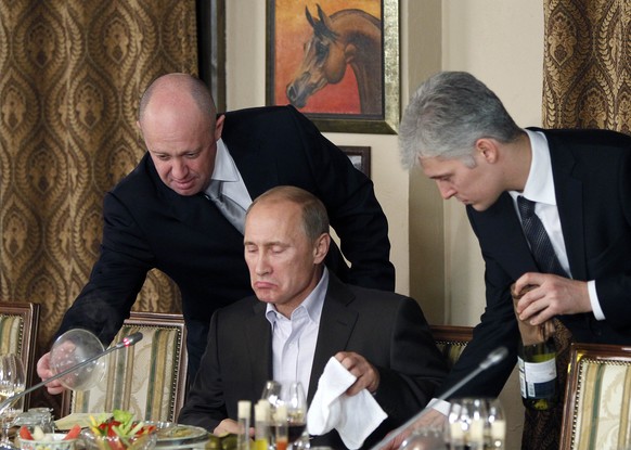 FILE - In this Friday, Nov. 11, 2011 file photo, businessman Yevgeny Prigozhin, left, serves food to Russian Prime Minister Vladimir Putin, center, during dinner at Prigozhin&#039;s restaurant outside ...