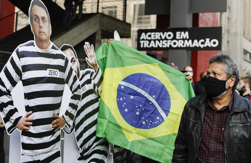 A man looks at a cardboard cutout of Brazilian President Jair Bolsonaro in prisoner garb during a demonstration against Bolsonaro&#039;s handling of the coronavirus pandemic and economic policies prot ...