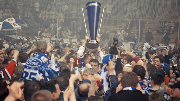 Umringt von Hunderten von Fans und Medienleuten stemmt ein Zuger Spieler am 11. April 1998 in der Davoser Eissporthalle den Meisterpokal in die Hoehe. Der EV Zug bezwang zuvor den HC Davos im sechsten ...