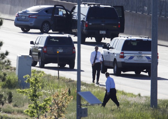 Denver Police Department detectives, foreground, investigate near where a Nissan sedan, top left, being driven by an Uber driver crashed into a retaining wall along Interstate 25 south of downtown Den ...