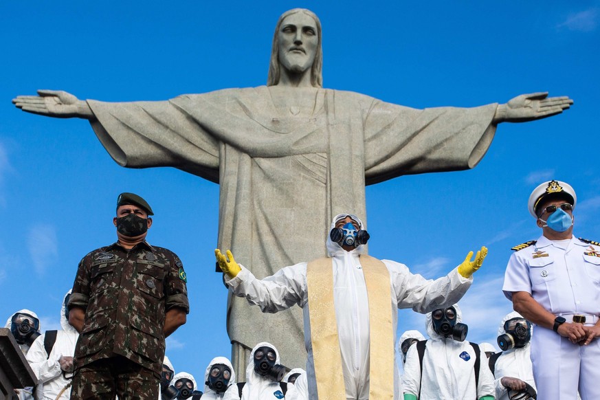 epa08601144 Reverend Omar (C) leads a short ceremony before soldiers of the Brazilian army disinfect the Cristo Redentor monument to reopen the tourist spot, in Rio de Janeiro, Brazil, 13 August 2020. ...