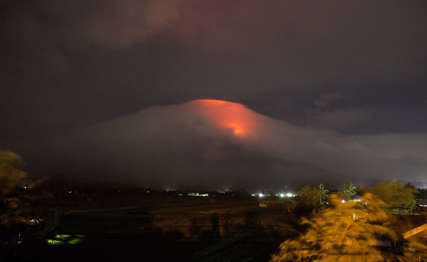 In this Sunday, Jan. 14, 2018, photo provided by Earl Recamunda, an orange glow is seen at the cloud-shrouded crater of Mayon volcano at Legazpi city, Albay province, about 340 kilometers (210 miles)  ...
