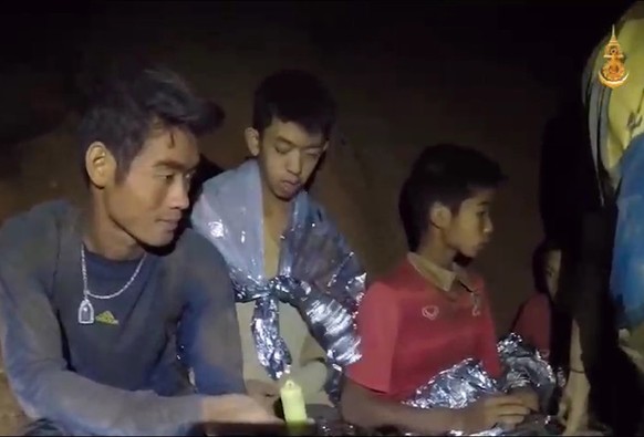 epa06862806 A video grab handout made available by Thai Royal Navy shows some of the members of a trapped soccer team in a section of Tham Luang cave in Khun Nam Nang Non Forest Park, Chiang Rai provi ...