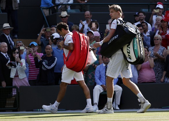 epa06880985 Kevin Anderson of South Africa (R) walks off court with Roger Federer of Switzerland whom he defeated in their quarter final match during the Wimbledon Championships at the All England Law ...