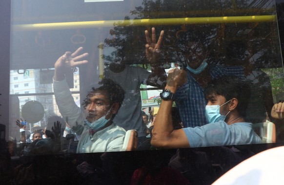 Arrested protesters flash the three-fingered salute while onboard a bus that is getting out of Insein prison and will transport them to an undisclosed location Wednesday, March 24, 2021 in Yangon, Mya ...