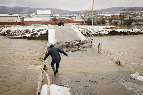 epa08931657 A local resident passes through the damaged bridge in the village of Dobroshec, Kosovo, 11 January 2021. Due to heavy rain showers the bridge that connects the village of Dobroshec with ot ...