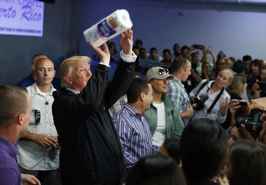 President Donald Trump tosses paper towels into a crowd as he hands out supplies at Calvary Chapel, Tuesday, Oct. 3, 2017, in Guaynabo, Puerto Rico. Trump is in Puerto Rico to survey hurricane damage. ...