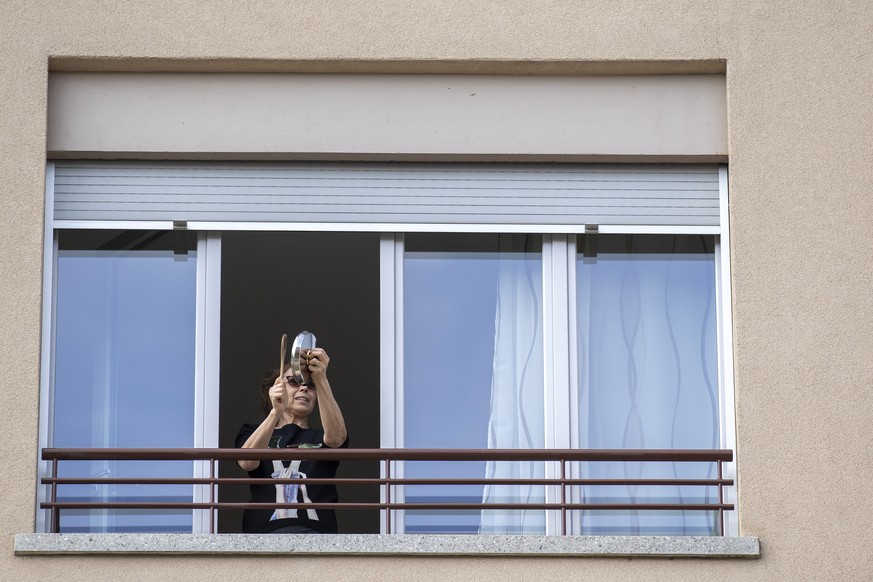 epa08309074 A woman applauds from her balcony to thank medical workers in Geneva, Switzerland, 20 March 2020. People all over the alpine nation were invited to take part in the &#039;Switzerland Says  ...