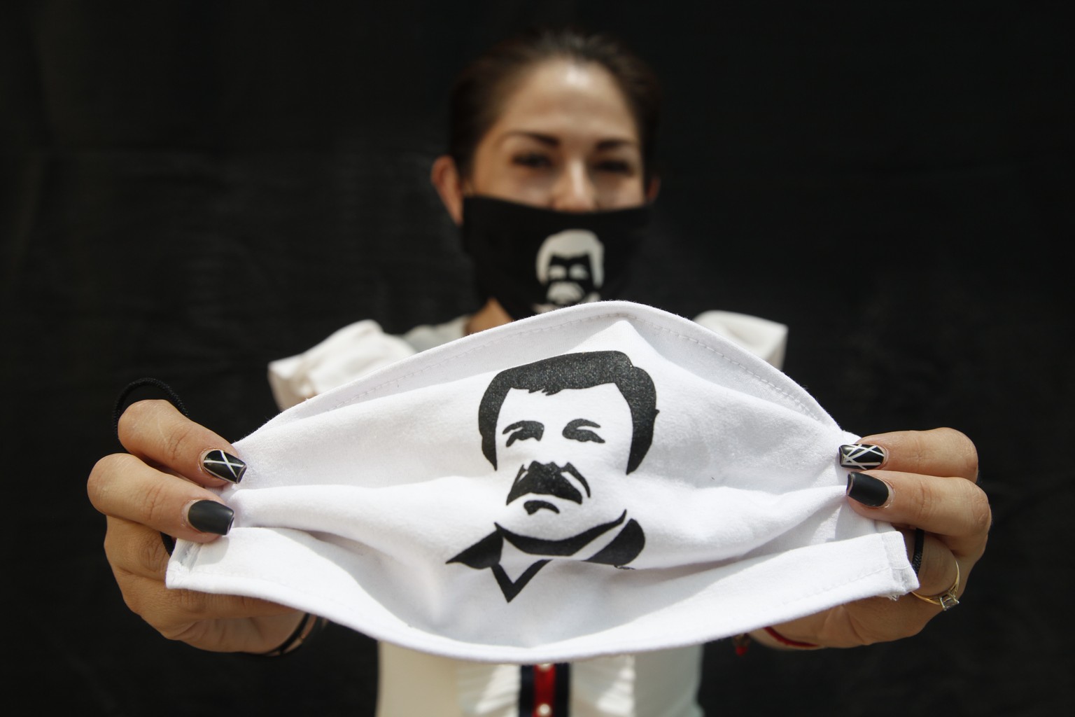 epa08367814 A person holds a face mask, which depicts famed drug lord Joaquin &#039;El Chapo&#039; Guzmanto, in Guadalajara, Jalisco, Mexico, 16 April 2020. According to media reports, Alejandrina Guz ...
