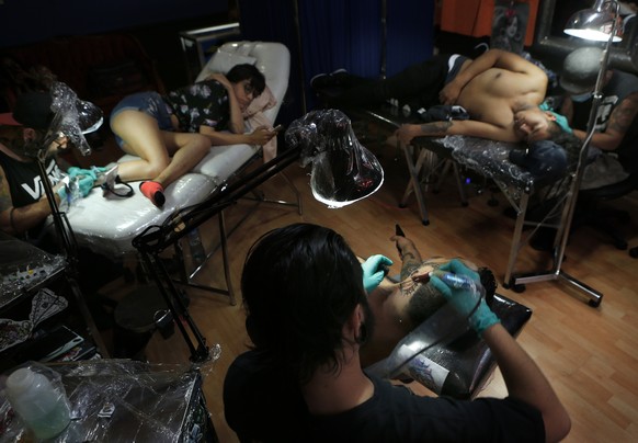 In this April 18, 2019 photo, tattoo artists Lalo Aguayo, left, Lalo Calva, center, and Emanuel Arana, work on clients Laura Reyes, Adrian Alonso Rodriguez and Jonathan Brannan, at the Corona Tattoo p ...