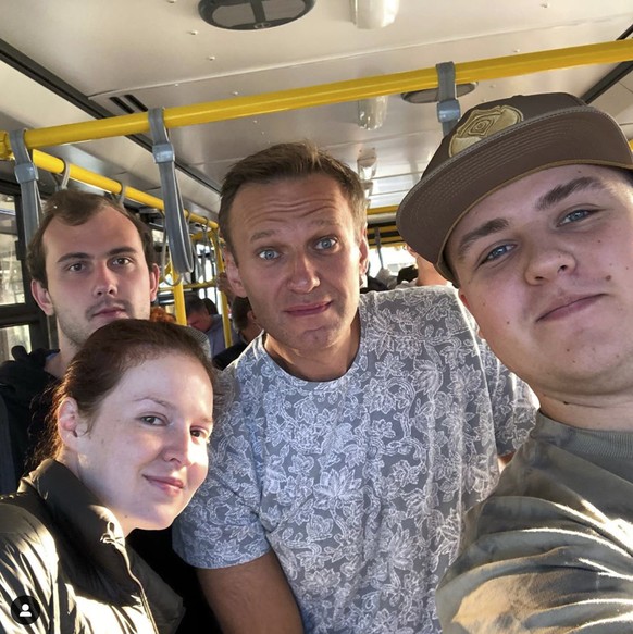 In this handout photo taken provided gluchinskiy, Russian opposition leader Alexei Navalny, center, and Kira Yarmysh, foreground left, pose for a selfie inside a bus on their way to an aircraft at an  ...