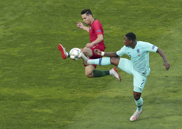 Portugal&#039;s Raphael Guerreiro, left, duels for the ball with Netherlands&#039; Steven Bergwijn during the UEFA Nations League final soccer match between Portugal and Netherlands at the Dragao stad ...