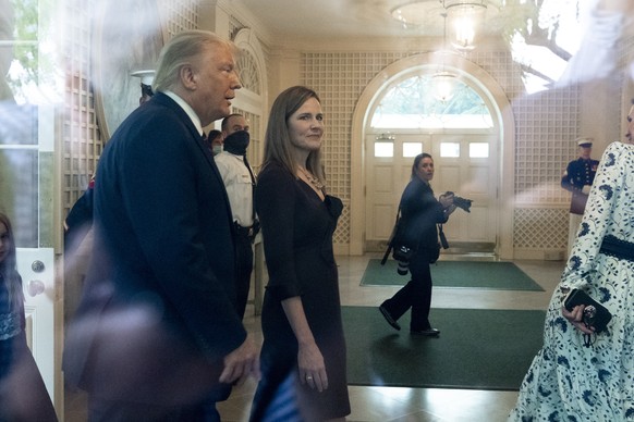 In an image taken through a window, President Donald Trump, left, and Judge Amy Coney Barrett, walk through the Palm Room after announcing Barrett as his nominee to the Supreme Court, in the Rose Gard ...