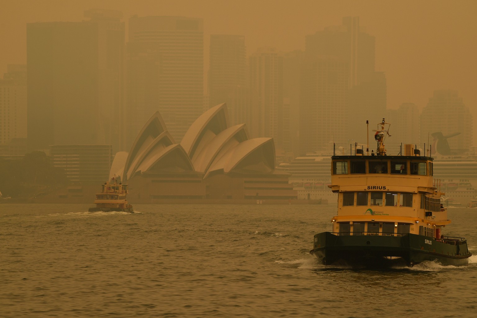 epa08080926 A ferry passes by the Sydney Opera House as smoke haze from bushfires in New South Wales blankets Sydney, Australia, 19 December 2019. Soaring temperatures exceeding 40 degrees Celsius and ...