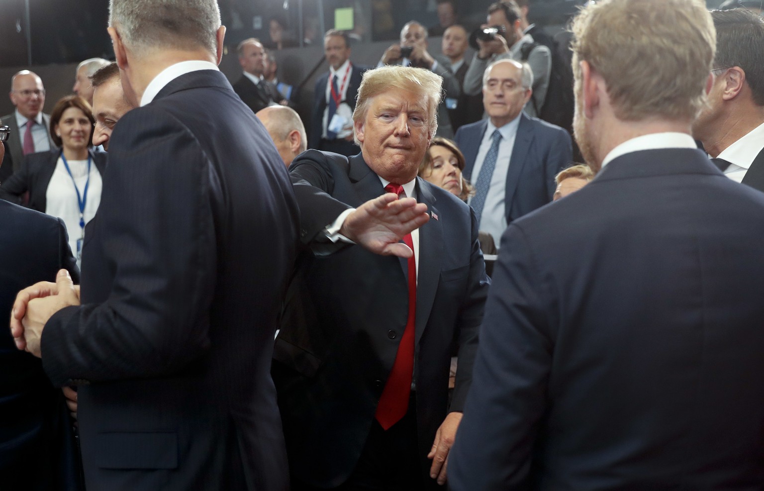 President Donald Trump pats a world leader on the back as he makes his way to his seat for a meeting of the North Atlantic Council during a summit of heads of state and government at NATO headquarters ...
