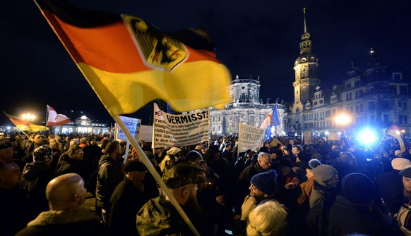 epa04538276 A supporter of the movement &#039;Pegida&#039; (Patriotic Europeans Against the Islamization of the Occident) wave German national flags during a rally against what Pegida claims to be exc ...
