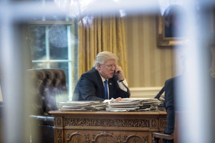 DAY 9 - In this Jan. 28, 2017, file photo, President Donald Trump speaks on the phone with German Chancellor Angela Merkel in the Oval Office at the White House in Washington. (AP Photo/Andrew Harnik, ...