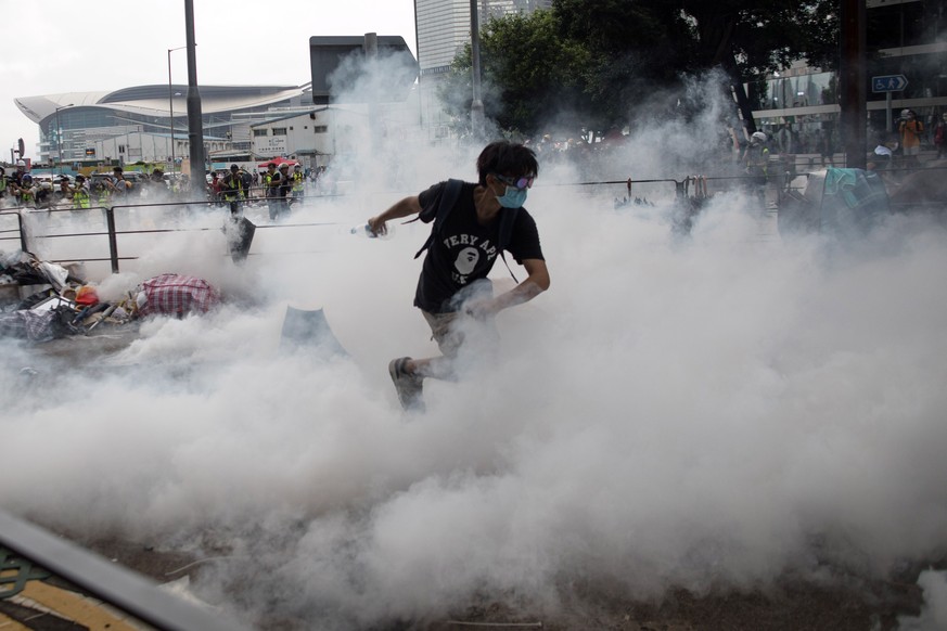 epa07643087 A protester runs away from tear gas shot by police during a rally against an extradition bill outside the Legislative Council in Hong Kong, China, 12 June 2019. The bill has faced immense  ...