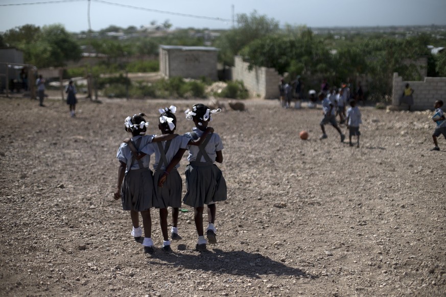 In this June 24, 2015 photo, schoolgirls walk through the rocky yard of Bethesda Evangelical School during a break in class, in Canaan, Haiti. In the case of Canaan, the fact homesteaders put their ow ...