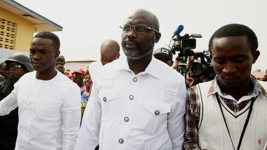 epa06405957 Liberian presidential candidate for the Coalition for Democratic Change (CDC), George Weah (C) leaves a polling station after casting his ballot in presidential elections run-off in Monrov ...