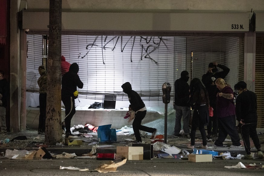 epa08455574 People loot a store in the Fairfax neighborhood during curfew as thousands of protesters take the street to demonstrate following the death of George Floyd, in Los Angeles, California, USA ...