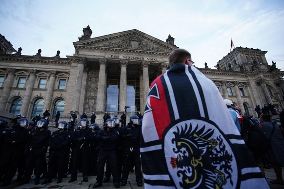 epa08634378 Demonstrators stand in front of the Reichstag building after trying to climb the stairs after protest against coronavirus pandemic regulations in Berlin, Germany, 29 August 2020. The initi ...