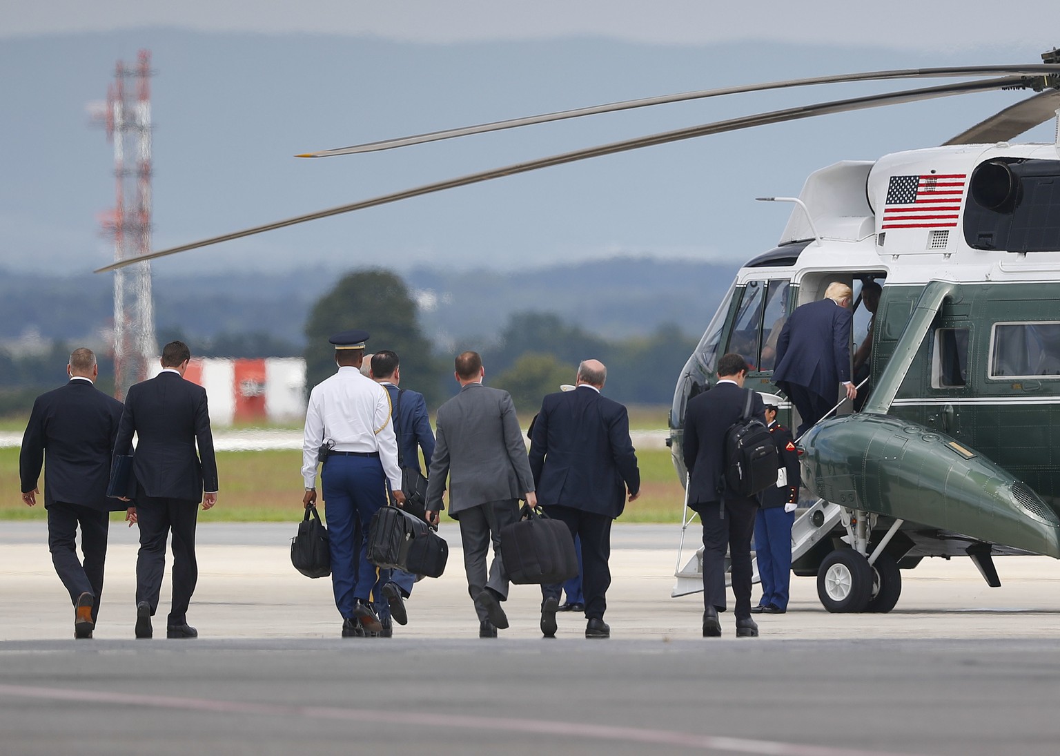 President Donald Trump, right, boards Marine One helicopter, followed by members of his staff at Hagerstown Regional Airport in Hagerstown, Md., Friday, Aug. 18, 2017, en route to nearby Camp David, f ...