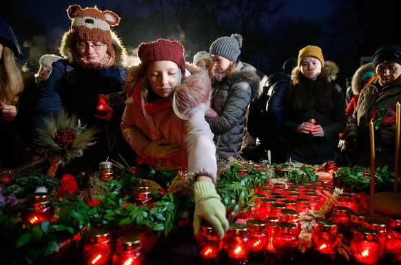 epa06350753 Ukrainians light candles and lay flowers during a memorial ceremony near a monument to the victims of the Great Famine in Kiev, Ukraine, 25 November 2017. Ukrainians light candles to mark  ...