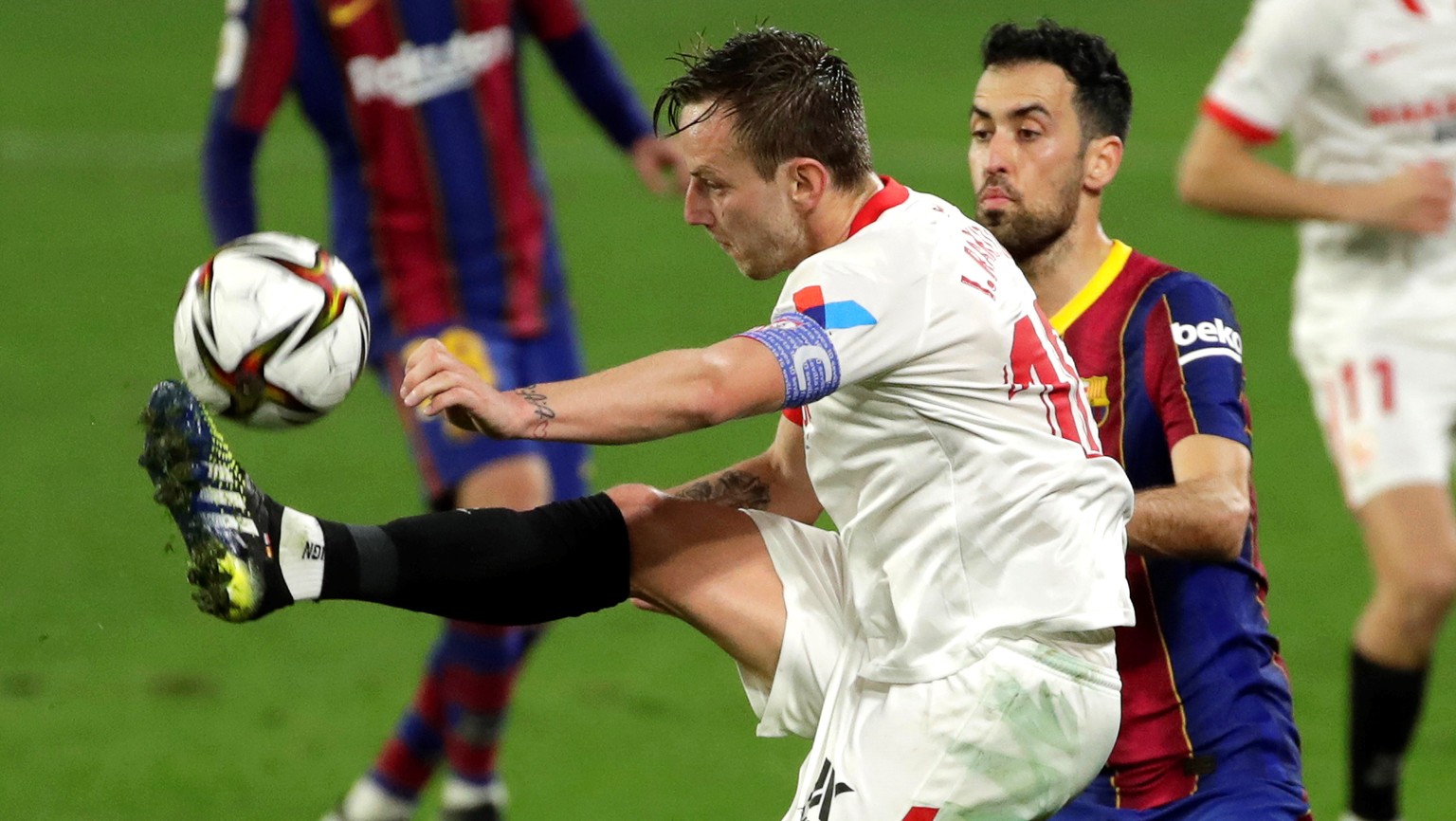 epa09002320 Sevilla&#039;s Ivan Rakitic (L) in action against FC Barcelona&#039;s Sergio Busquets (R) during the Spanish King&#039;s Cup semi final, first leg soccer match between Sevilla FC and FC Ba ...