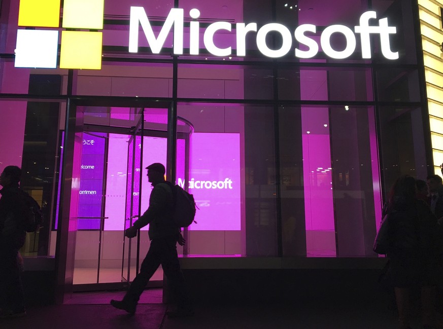 FILE - In this Nov. 10, 2016, file photo, people walk near a Microsoft office in New York. Microsoft, on an accelerated growth push, is buying speech recognition company Nuance in a deal worth $19.7 b ...