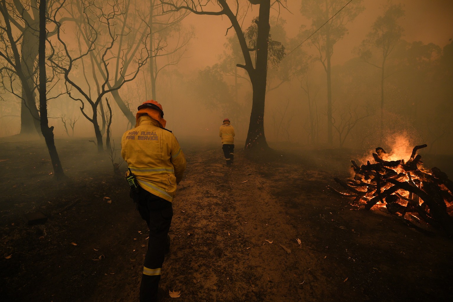 epa08048059 New South Wales (NSW) Rural Fire Service (RFS) and Fire and Rescue NSW crews work to protect a property in Kulnura as the Three Mile fire approaches Mangrove Mountain, Australia, 06 Decemb ...