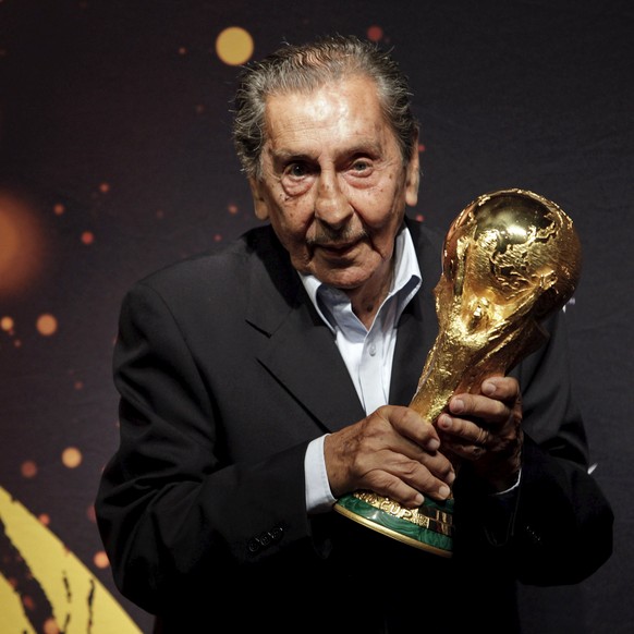 Former Uruguayan soccer player Alcides Ghiggia, famed for his role in the final 1950 World Cup match between Uruguay and Brazil, poses with the FIFA World Cup trophy during the 2014 FIFA World Cup Tro ...