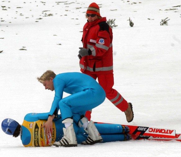 A paramedic, background, rushes to the scene as overall World Cup winner Janne Ahonen of Finland, on ground, is helped by his fellow countryman Risto Jussilainen, front, after a bad landing during the ...