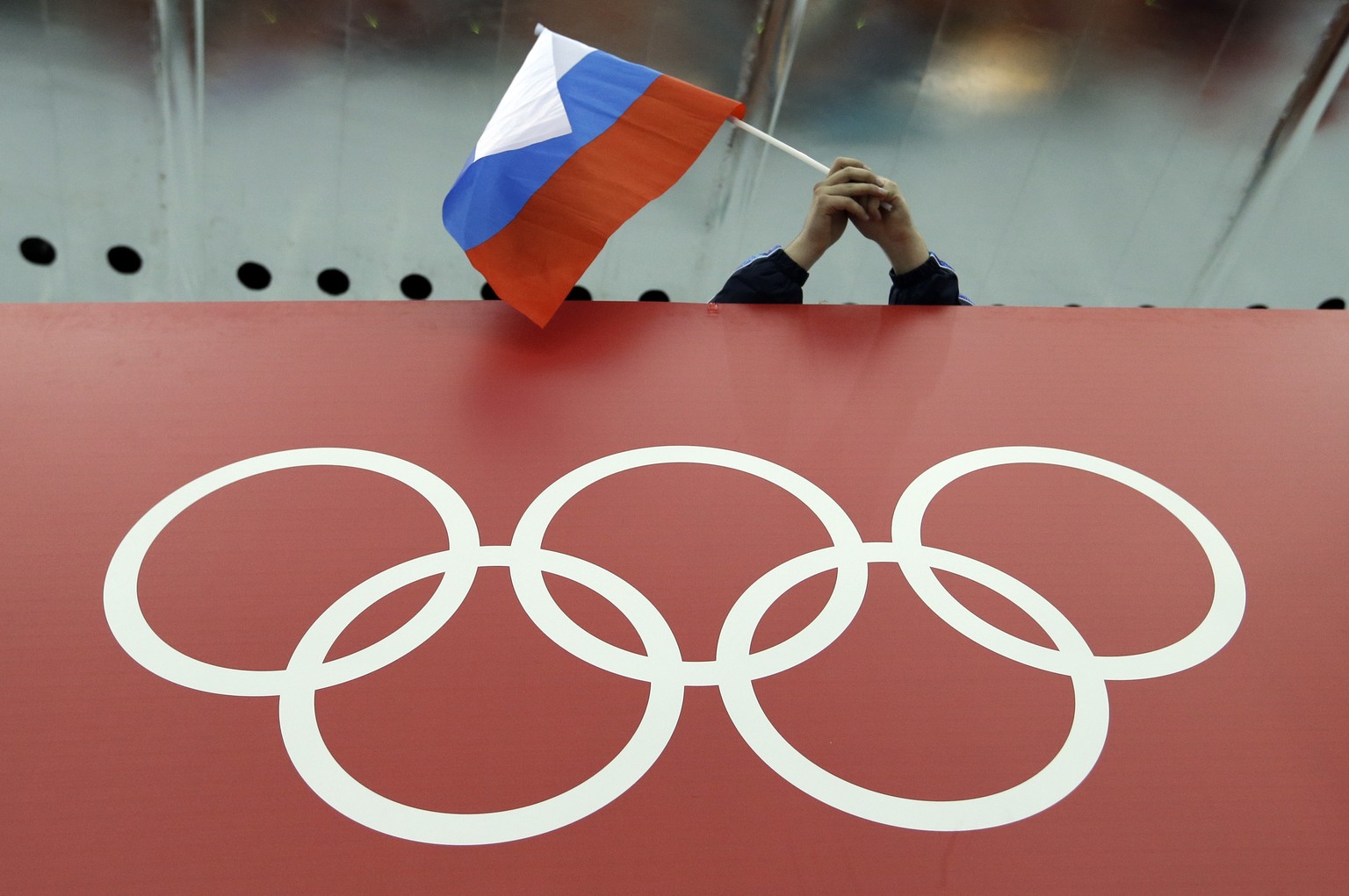 FILE - In this Feb. 18, 2014, file photo, a Russian skating fan holds the country&#039;s national flag over the Olympic rings before the start of the men&#039;s 10,000-meter speedskating race at Adler ...