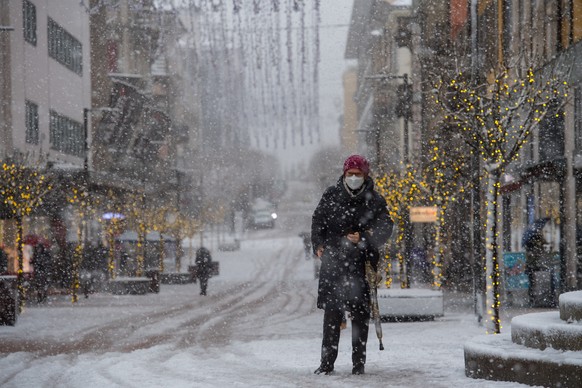 Eine Fussgaengerin bei Schnellfall in der Innenstadt von Bellinzona, am Freitag, 4. Dezember 2020. Das Tessin ist am Freitagmorgen unter einer Schneedecke aufgewacht. Es galt Gefahrenstufe vier von fu ...