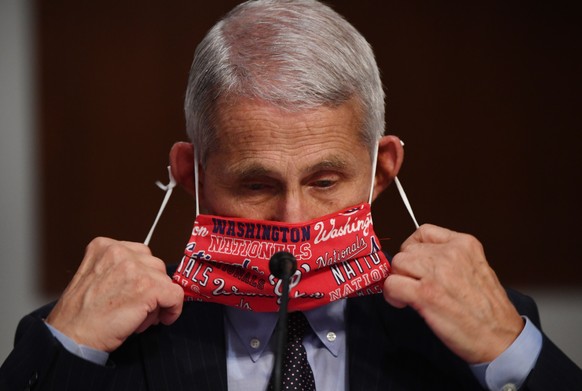epa08518140 Dr. Anthony Fauci (L), director of the National Institute for Allergy and Infectious Diseases, removes his face mask as he testifies before the Senate Health, Education, Labor and Pensions ...