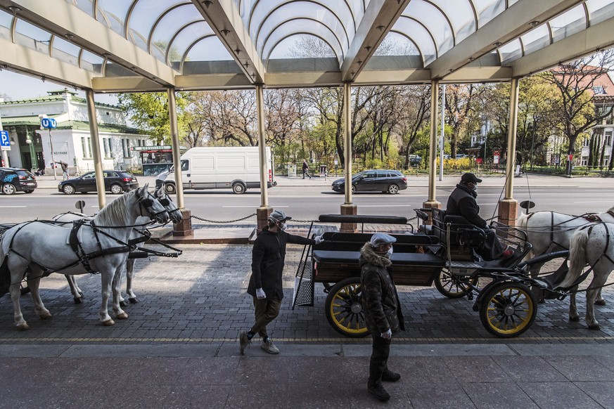 epa08341676 Coachmen wearing face masks wait on their &#039;Fiaker&#039; (fiacre, a horse-drawn carriage) for food packages for delivery in front of the InterContinental Hotel in Vienna, Austria, 03 A ...
