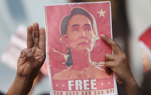 FILE - In this Feb. 8, 2021, file photo, Myanmar nationals living in Thailand hold pictures of Myanmar leader Aung San Suu Kyi gesture with a three-fingers salute, a symbol of resistance, as they prot ...