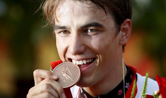 epa01463329 Nino Schurter of Switzerland bites his bronze medal during the medal ceremony for the Men`s Cross Country at Laoshan Mountain Bike Course at the Beijing 2008 Olympic Games, Beijing, China, ...